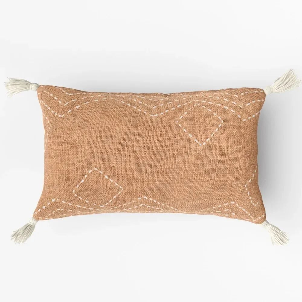 Product visualization for catalogs showing a brown pillow with stitched white geometric patterns and tassels