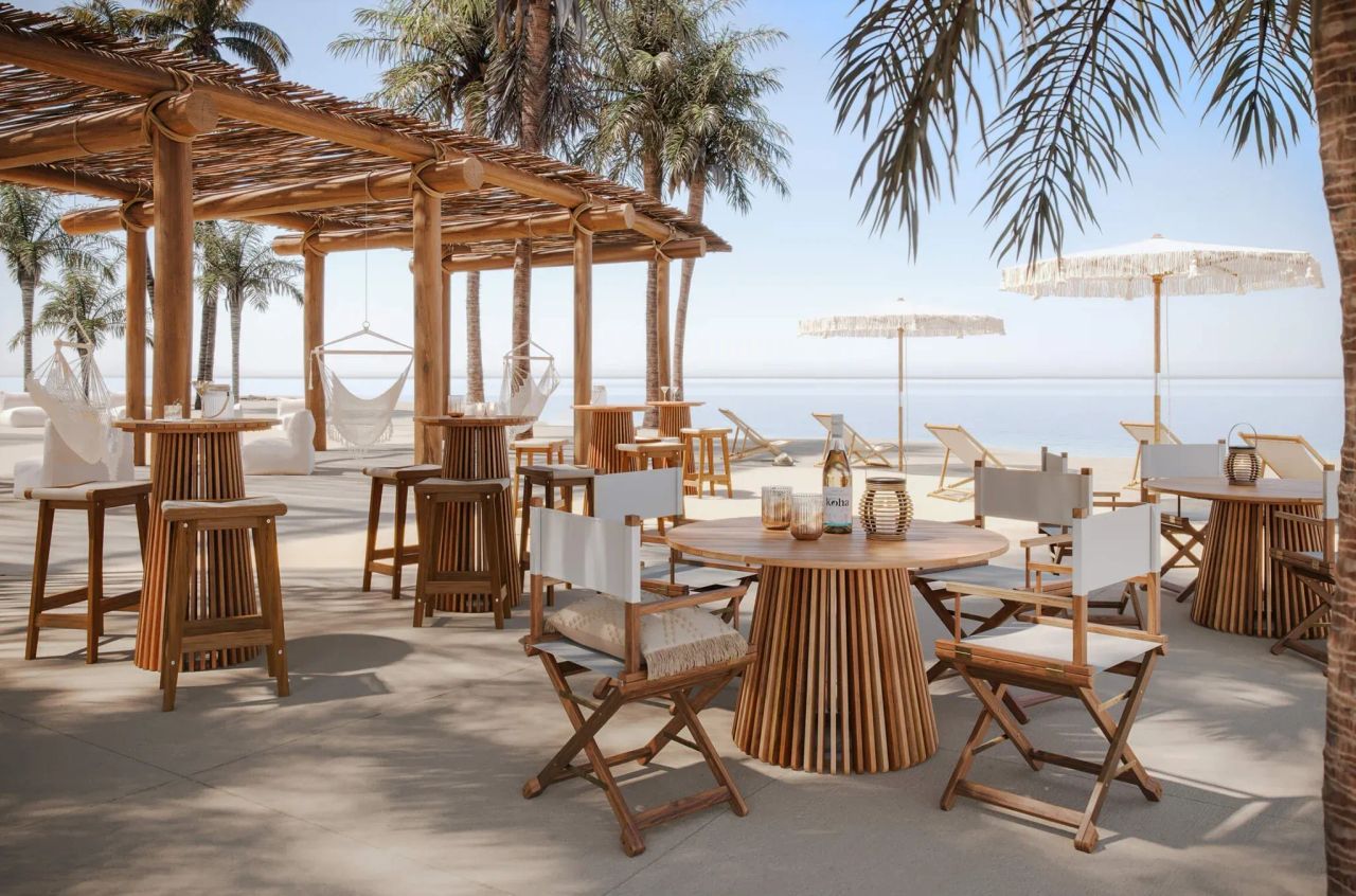 3D visualization of beach café with wooden tables, chairs, pergola, hammocks, and ocean view